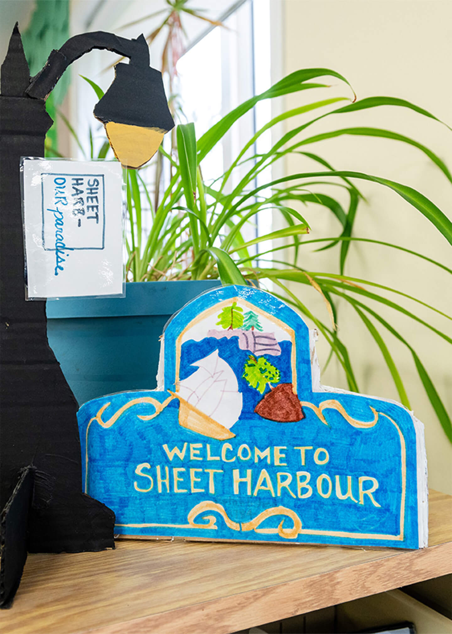 Hand made art piece on a desk that is a lamp post and welcome to sheet harbour sign